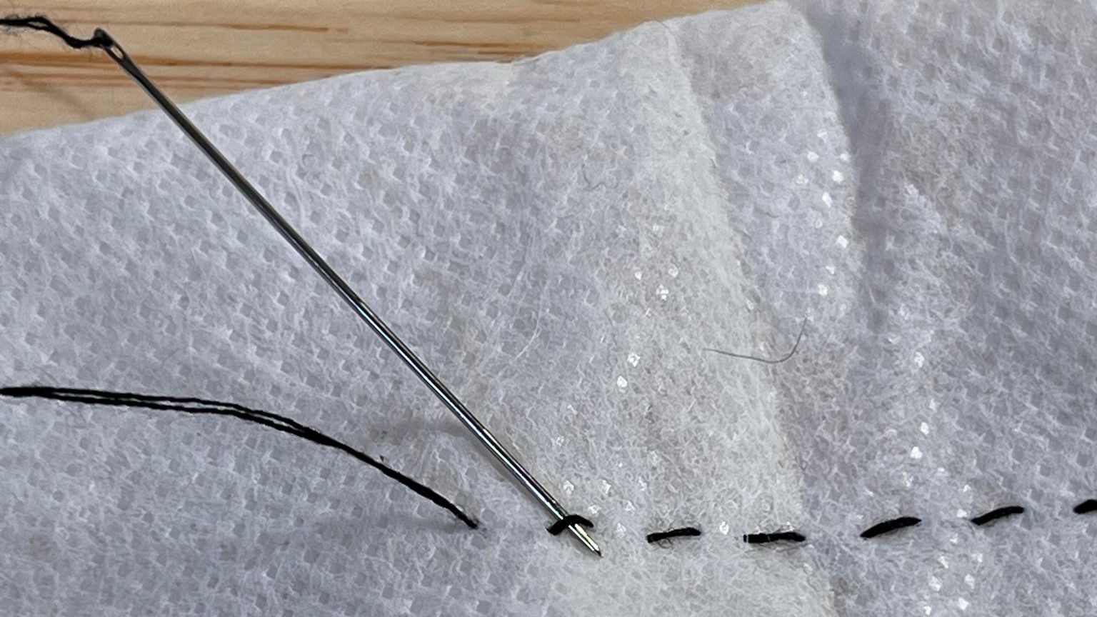 Thread the point of your needle between the bottom of your last stitch and the fabric.